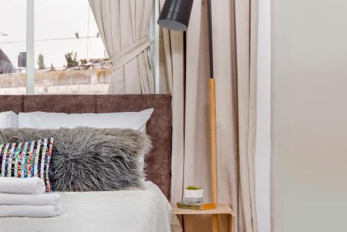 a bed with a gray pillow and a window at Havatselet 19 By Isrentals in Jerusalem