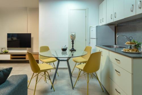 a kitchen with a glass table and yellow chairs at Havatselet 19 By Isrentals in Jerusalem