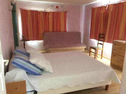 a bedroom with a large white bed and a chair at Chez Laurette in Mirabel-aux-Baronnies