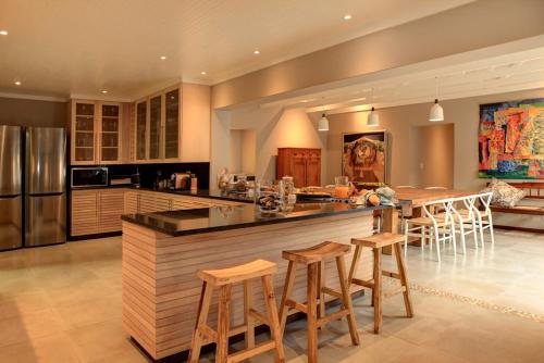 a large kitchen with a bar with stools in it at Scallop Lodge in Plettenberg Bay