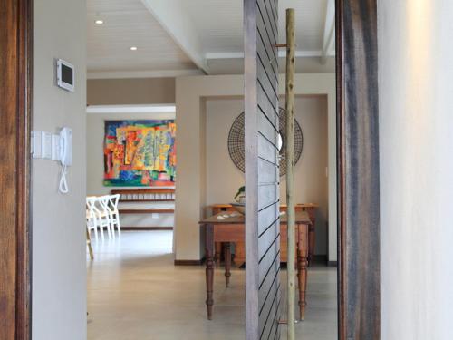 a dining room with a table and a painting on the wall at Scallop Lodge in Plettenberg Bay