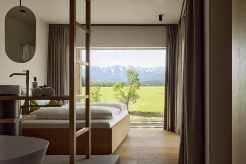 a bedroom with a bed and a large window with mountains at Hotel BERGEBLICK in Bad Tölz