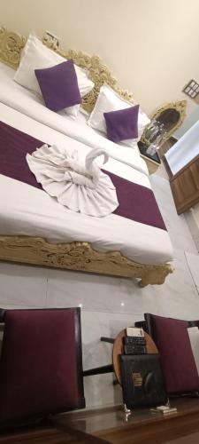 two beds with purple and white pillows and a telephone at Perfectstayz Premium @Harkipauri Road in Haridwār