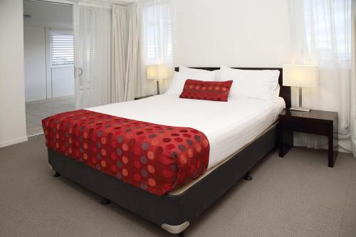 a bedroom with a large bed with a red pillow at Cairns Central Plaza Apartment Hotel Official in Cairns