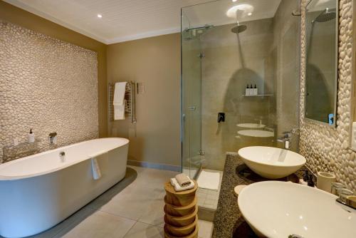 a bathroom with a tub and a sink and a shower at Scallop Lodge in Plettenberg Bay