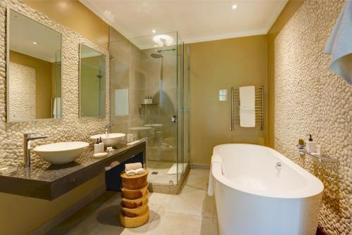 a bathroom with a tub and two sinks and a shower at Scallop Lodge in Plettenberg Bay