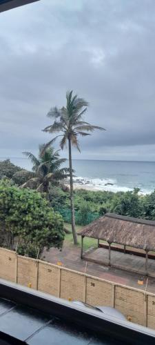a view of a beach with a bench and palm trees at Unwind and Relax in Amanzimtoti
