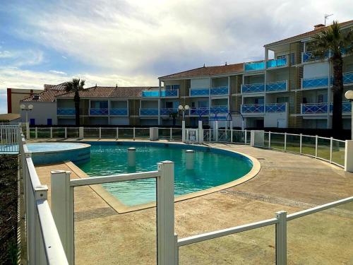 une piscine en face d'un grand bâtiment dans l'établissement Beach house - 6 people - parking, à Frontignan