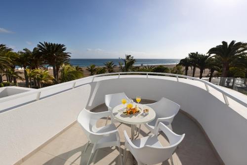 a table and chairs on a balcony with the beach at Hipotels La Geria in Puerto del Carmen