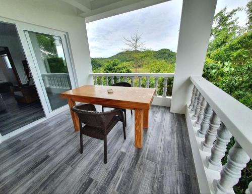a wooden table and chairs on a porch with a window at Tablas Seaview Homestay in Ferrol