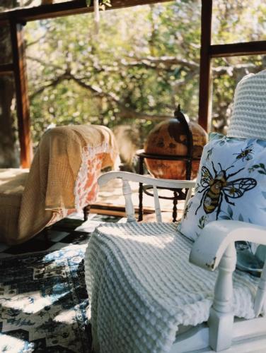 a porch with a chair with a pillow with a bee on it at 11 Mountain Stream Hot Tub Self Catering in Gordonʼs Bay