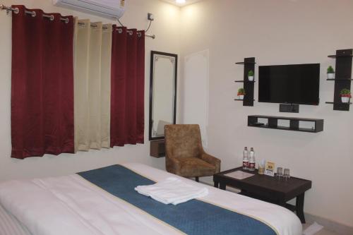Un dormitorio con una cama y una silla y un televisor. en Pavitram Hotel & Banquet, en Ranchi