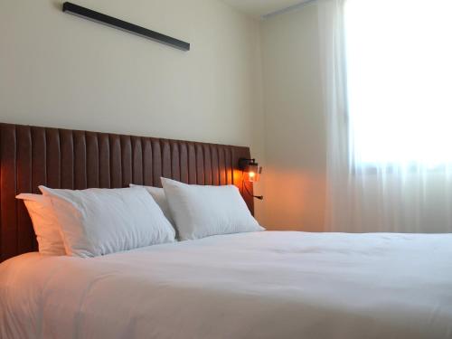 a large bed with white pillows and a window at Adonis le Castellet in Signes