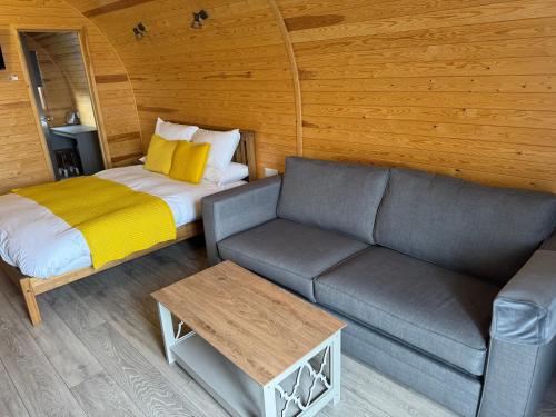 a living room with a couch and a bed at Ffrith Park hotel pods in Prestatyn