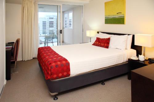 a bedroom with a large bed with red pillows at Cairns Central Plaza Apartment Hotel Official in Cairns