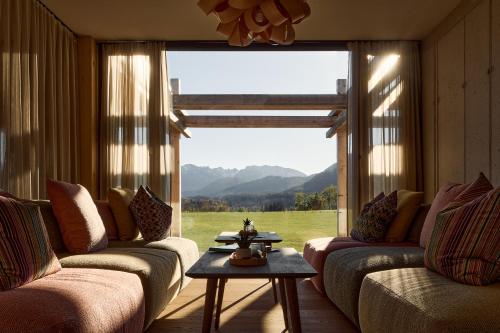 a living room with two couches and a large window at Hotel BERGEBLICK in Bad Tölz