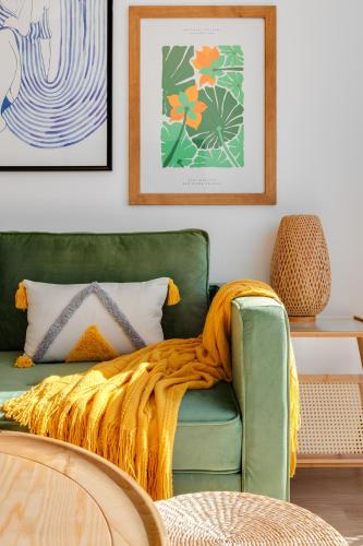 a living room with a green couch with a blanket at way2sun penthouses Gran Alacant - FREE e-bikes & jacuzzi & solarium & PS5 in Gran Alacant