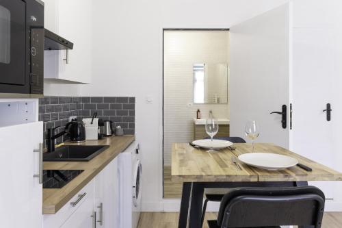 a kitchen with a table with two wine glasses on it at Segré centre ? studio ? 24m² ? cuisne ? wifi ? TOUT NEUF! in Segré