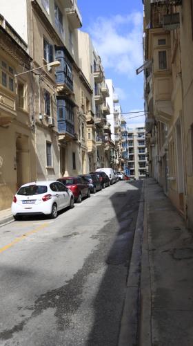 a street with cars parked on the side of a building at Candid Aura Studio Chic Sliema Basement Apartment in Il-Gżira taʼ Forti Manoel