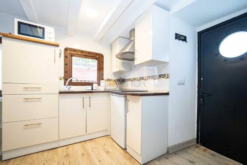 een keuken met witte kasten en een zwarte deur bij Les Moraes By Silastur in Cudillero