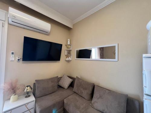 a living room with a couch and a flat screen tv at Blue Horizon Seaside Studio in Nea Kalikratia