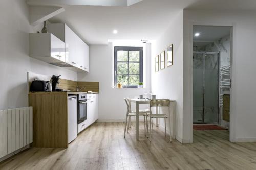 a kitchen with white cabinets and a table and chairs at T2 Duplex Segré - Hyper centre - Wifi - Netflix in Segré