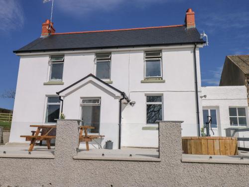 a white house with a picnic table in front of it at Llanwern Farm in Fishguard