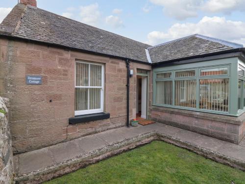 an exterior view of a brick house with a yard at Dromore Cottage in Berwick-Upon-Tweed