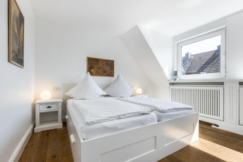 Un dormitorio blanco con una cama blanca y una ventana. en Haus Victoria, en Westerland