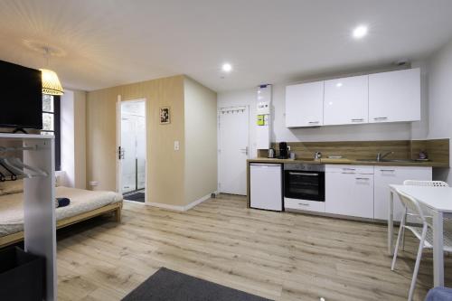 une grande cuisine avec des armoires blanches et une table dans l'établissement Studio Cosy Hyper centre - Fibre - Netflix, à Segré