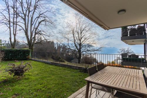 a backyard with a wooden table and a fence at Les terrasses du Lavaux in Puidoux