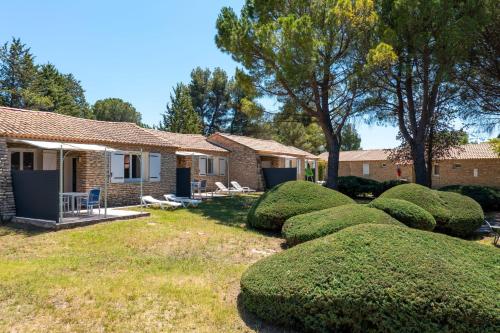 une rangée de buissons joliment parés devant une maison dans l'établissement Pretty little house in a tourist residence, à La Roque-sur-Pernes