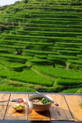 a bowl of food sitting on a table in front of a field at Hiếu Hương Homestay in Lũng Tiềm