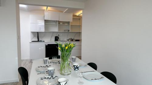 a white dining room with a table with yellow flowers at Villa Leopold - apartmánový dům in Karlovy Vary