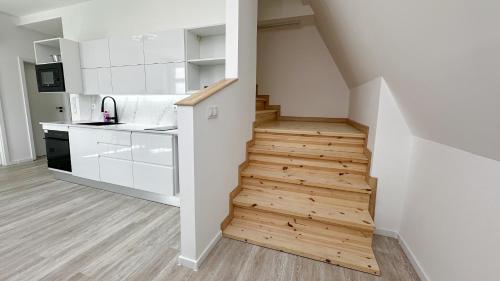 a kitchen with white cabinets and a wooden staircase at Villa Leopold - apartmánový dům in Karlovy Vary