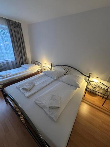 a bedroom with two beds with white sheets and a window at Hotel-Pension Asta in Munich
