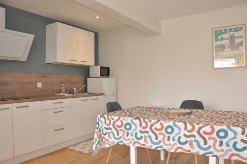 a kitchen with a table and white cabinets at gîte du Cellier nantais in Le Cellier