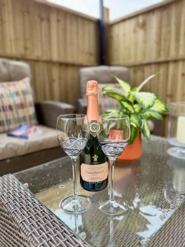 a bottle of champagne and two glasses on a table at Acorn Lodge Pentewan in St Austell