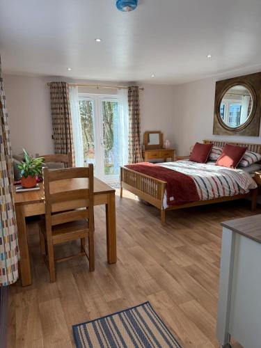 a bedroom with a bed and a table and a window at Acorn Lodge Pentewan in St Austell
