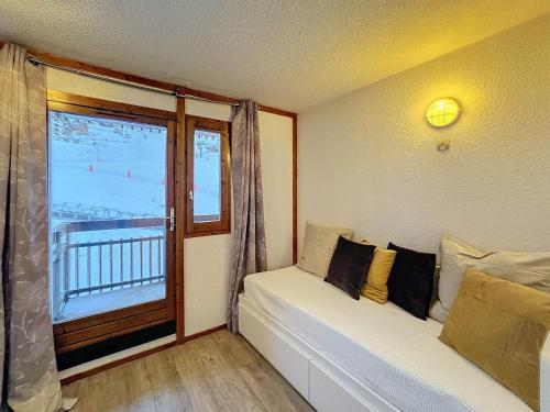 Cette chambre dispose d'une fenêtre et d'un canapé avec des oreillers. dans l'établissement Studio cabine 4 pers, ski aux pieds, carrefour central, PARKING - FR-1-178-105, aux Menuires