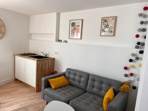 a living room with a couch and a kitchen at Studio atypique et chaleureux coeur d'Ancenis in Ancenis