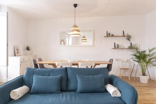 a living room with a blue couch and a table at grand gîte terrasse vue Loire et château d'Ancenis in Ancenis