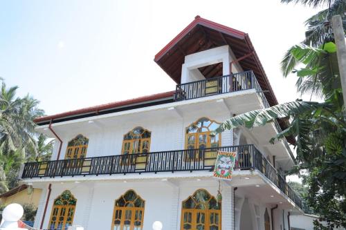 a white house with a balcony on top of it at J & J Homestay in Jaffna