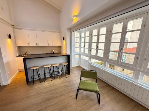 a kitchen with a bar and stools in a room with windows at PADRÓN PLAZA Lofts, Centro in Padrón