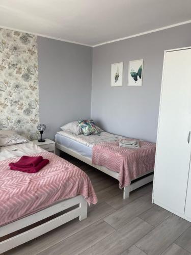 a bedroom with two beds with pink sheets at Dom Gościnny "Zawiśle" in Włocławek
