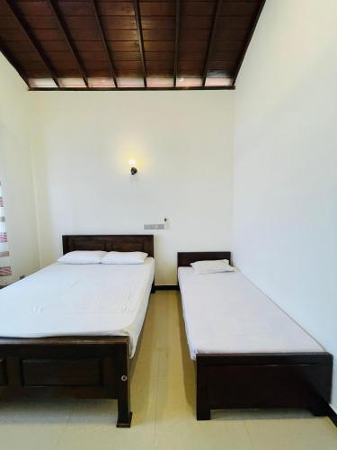 two beds sitting next to each other in a room at Emerald Villa in Matara