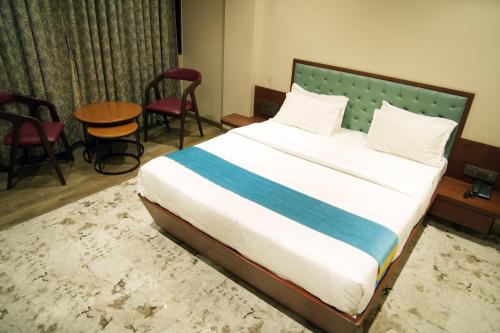 a large bed in a room with chairs and a table at Hotel Yashoda in Pune