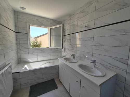 a bathroom with two sinks and a tub and a window at gîte des Maraires in Mésanger