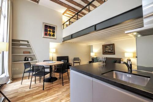 une cuisine avec un évier et une table avec des chaises dans l'établissement Molière ChicSuites, à Paris