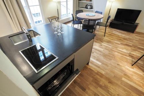 une cuisine avec un comptoir noir et un salon dans l'établissement Molière ChicSuites, à Paris